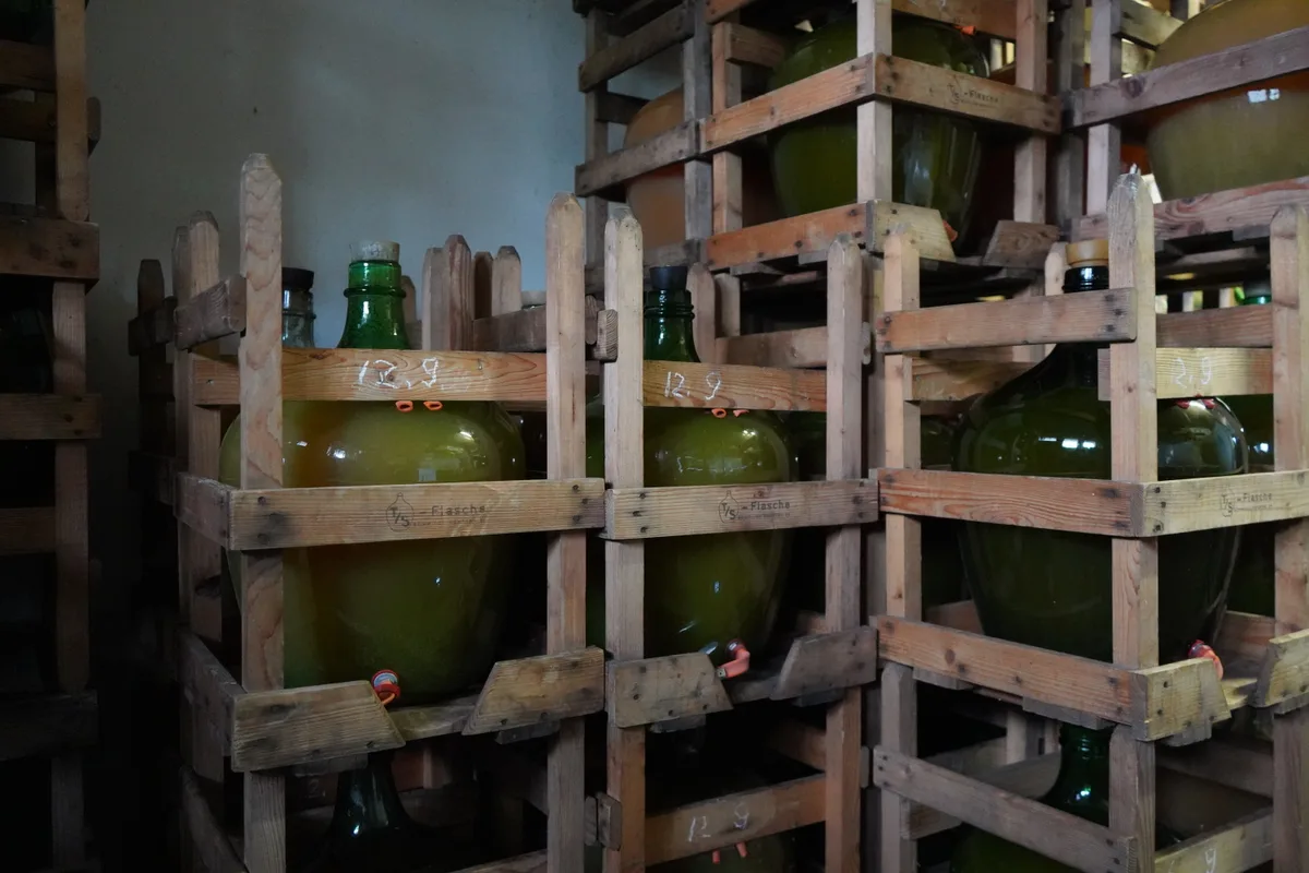Grosse Mostflaschen lagern in Gestellen.